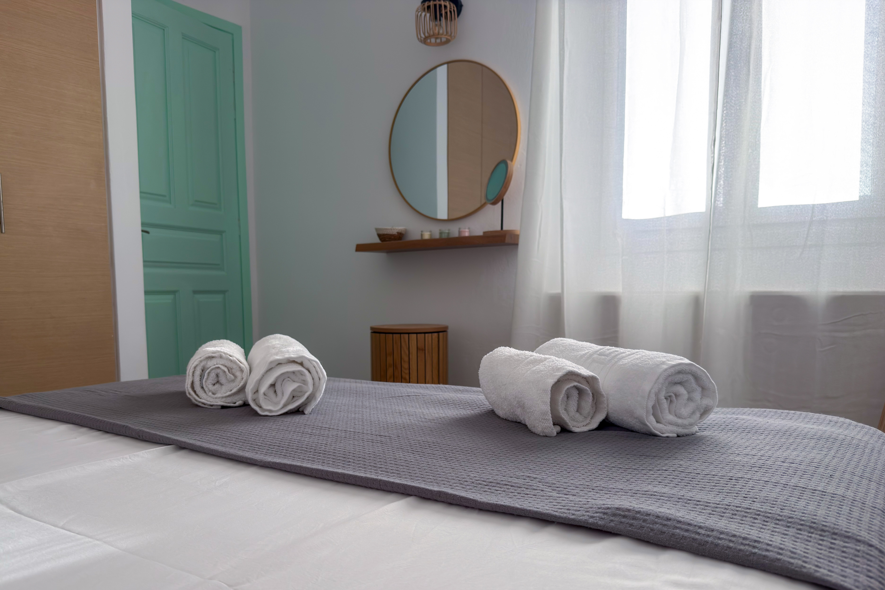 Bedroom with white linen and rolled towels